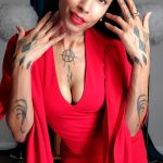 An elegant lady with intricate tattoos adorning her hands, looking stunning in a Valentino inspired red dress.