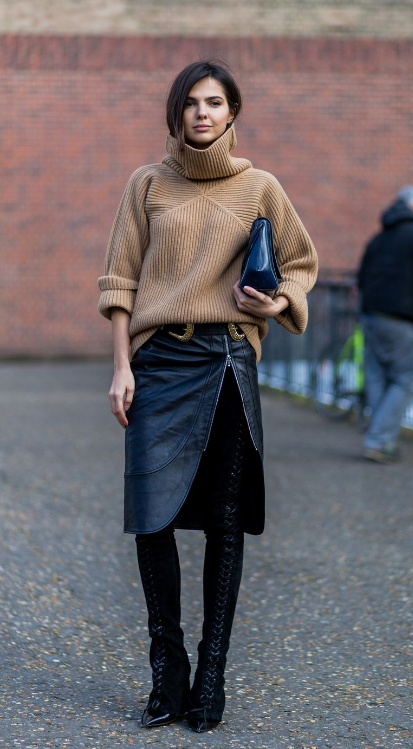 A woman wearing a camel sweater and leather skirt, exuding elegance and style