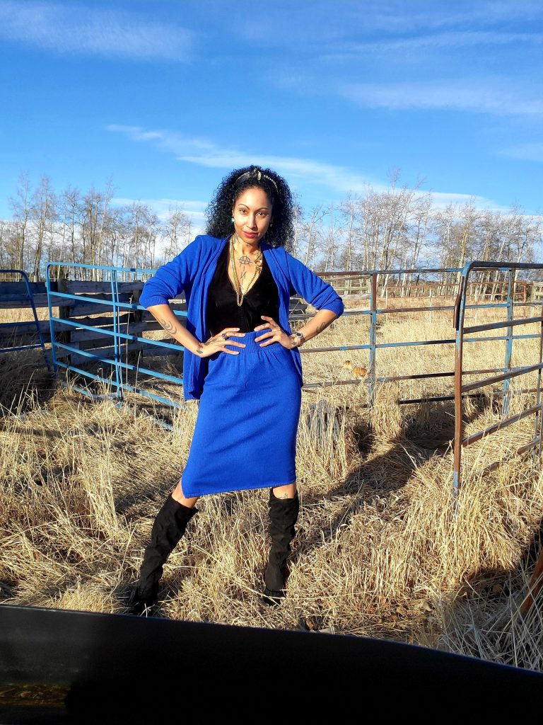 Fashionable woman in a blue dress strikes a pose in the countryside, dressed in a vintage 1980s royal blue cardigan and skirt ensemble