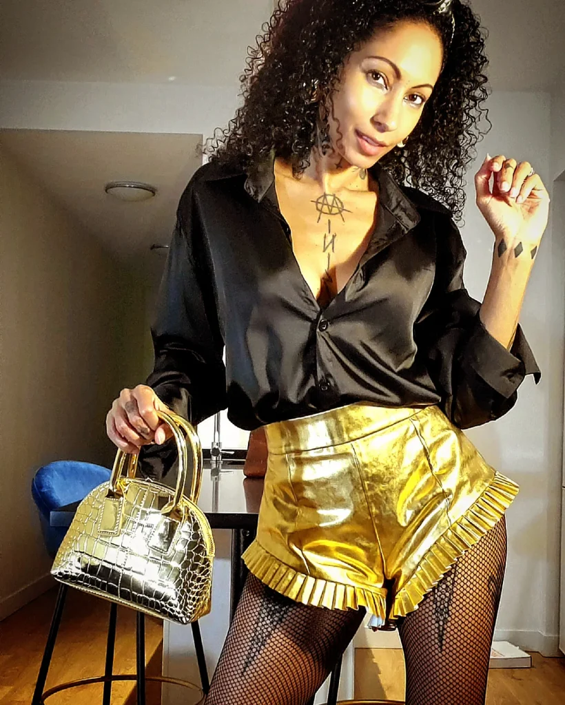 Stylish lady in gold outfit, including metallic shorts and satin blouse, posing for a picture