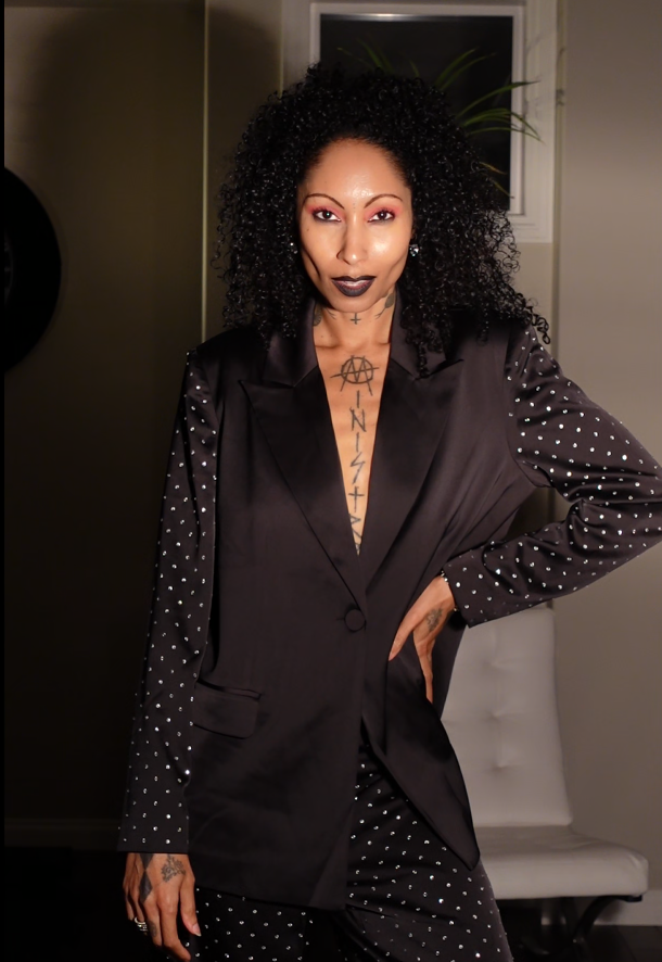 A stylish woman with tattoos wearing a sleek black suit