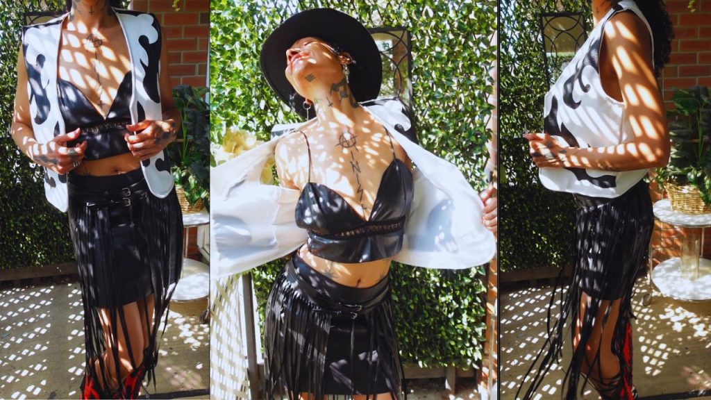 Elegantly dressed in a white shirt and leather skirt, a woman flaunts her fashionable cowboy boots with poise.